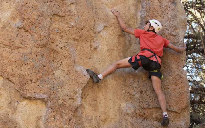 a teen climbs a rock wall on an outward bound course in oregon